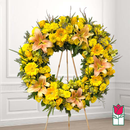 Yellow floral wreath on a standing easel with peach lilies