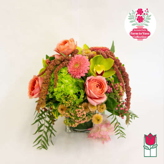 Mixed bouquet with pink and peach flowers in a clear vase