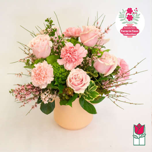 Pink roses and carnations arranged in a pale vase