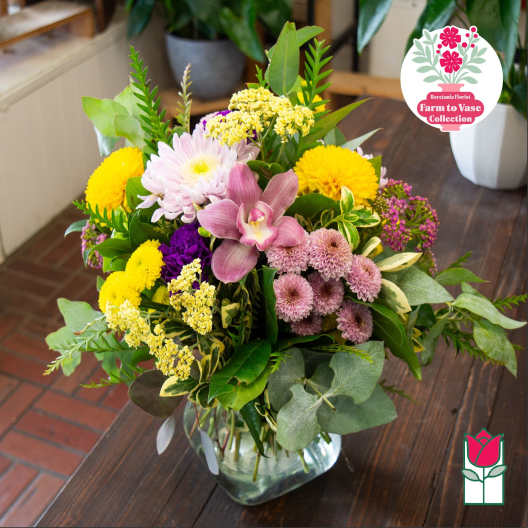Mixed bouquet in a clear glass vase with pink, yellow, and purple flowers