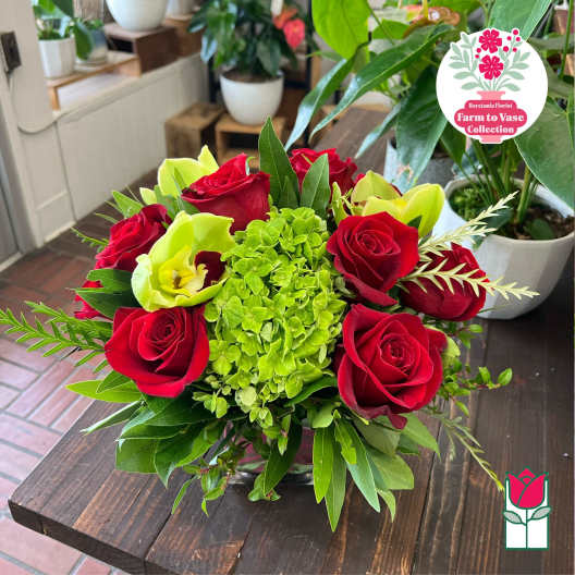 Red roses and lime-green blooms arranged in a low glass vase