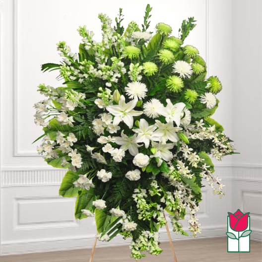 Large white and green funeral spray with lilies and orchids on a stand