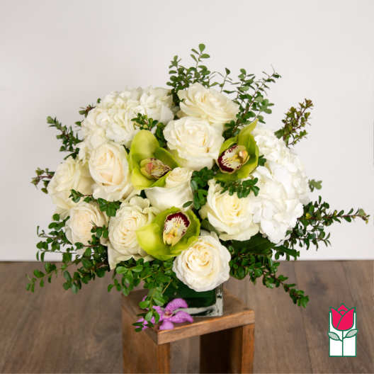 White roses and hydrangeas with green orchids in a glass vase