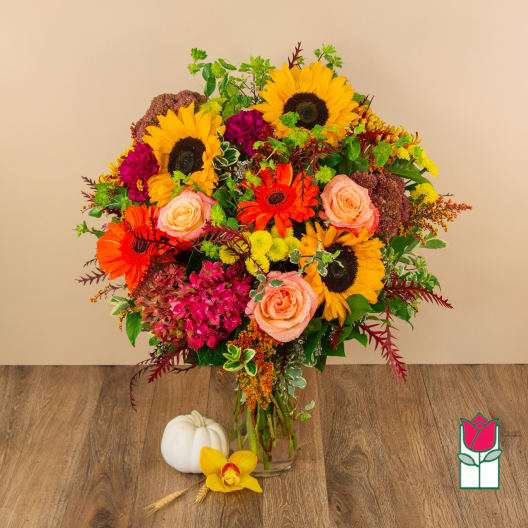 Mixed bouquet with sunflowers, roses, and gerbera daisies in a glass vase