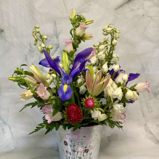 Mixed bouquet with purple irises and pink-white blooms in a decorative metal bucket