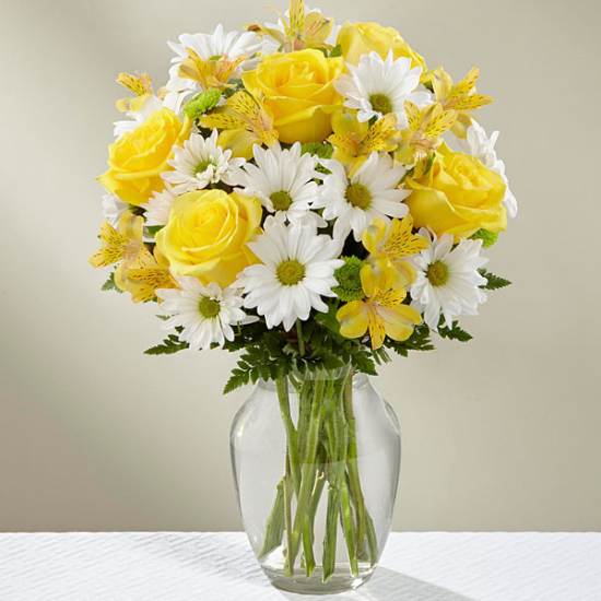Yellow roses and white daisies in a clear glass vase