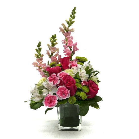 Pink roses and carnations in a clear glass vase with tall pink snapdragons