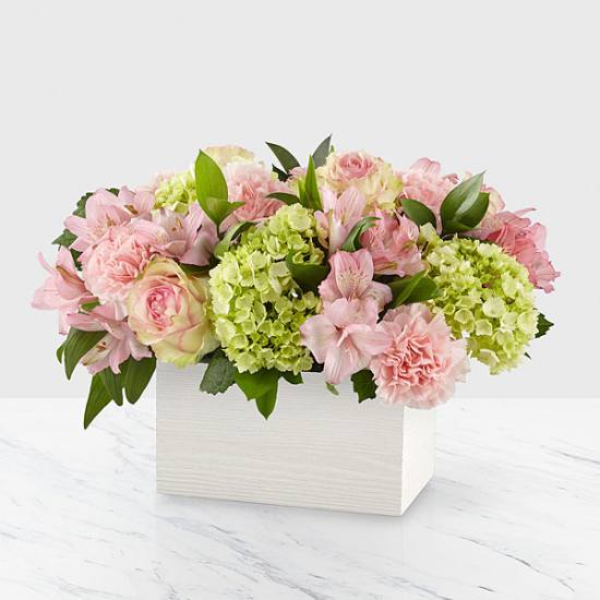 Pink flowers and green hydrangeas arranged in a white box