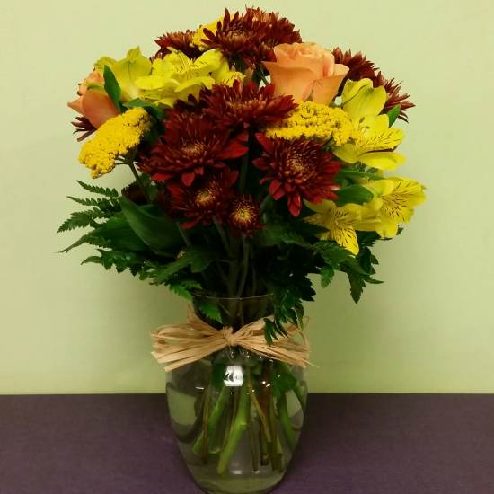 Bouquet of yellow and peach flowers in a glass vase