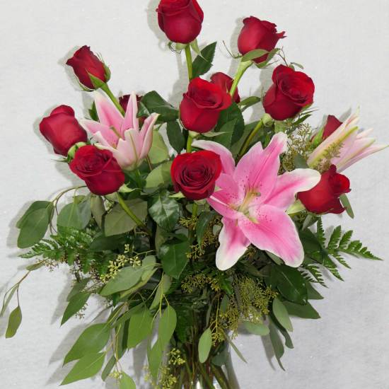 Bouquet of red roses and pink lilies in a clear glass vase