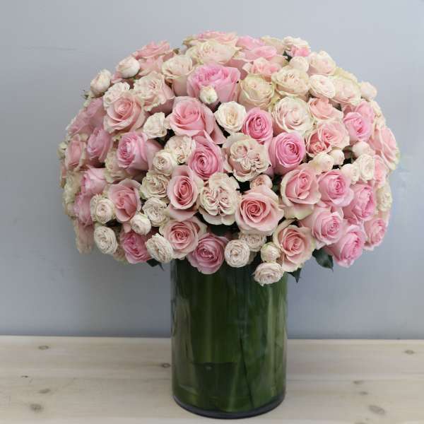Large dome of pink and ivory roses in a tall glass cylinder vase