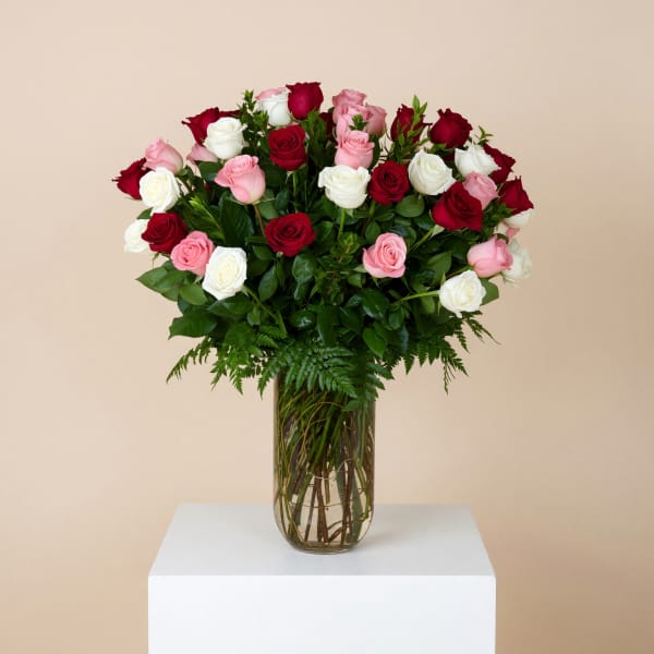 Bouquet of red, pink, and white roses in a clear glass vase