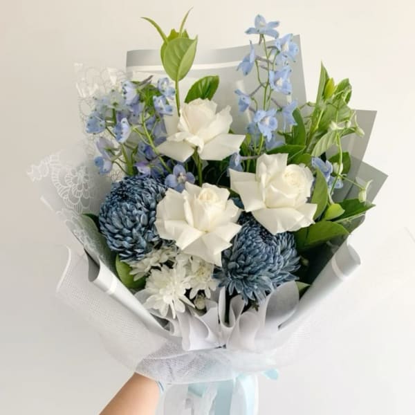 Blue and white bouquet with roses, chrysanthemums, and delphinium wrapped in white paper