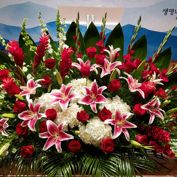 Large floral spray with pink lilies, red roses, and white hydrangeas