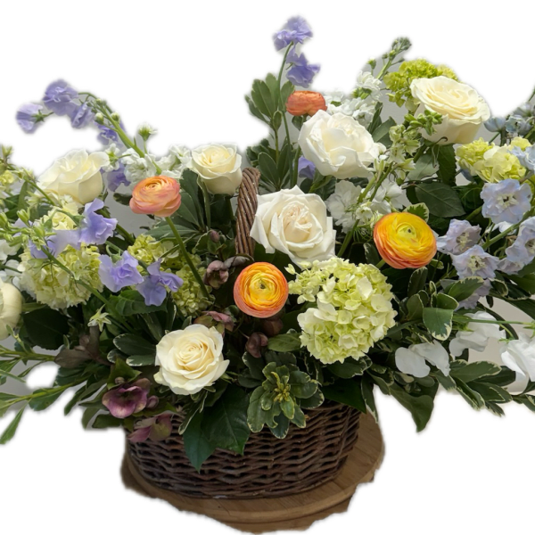 Basket arrangement of white roses, ranunculus, and pastel blue flowers