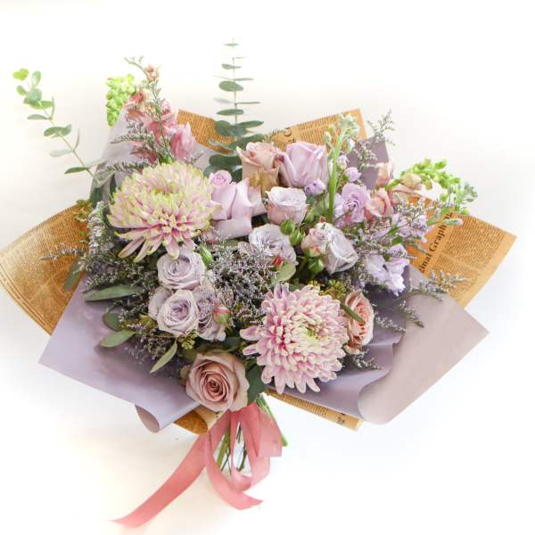 Bouquet of pastel roses and chrysanthemums wrapped in lavender paper