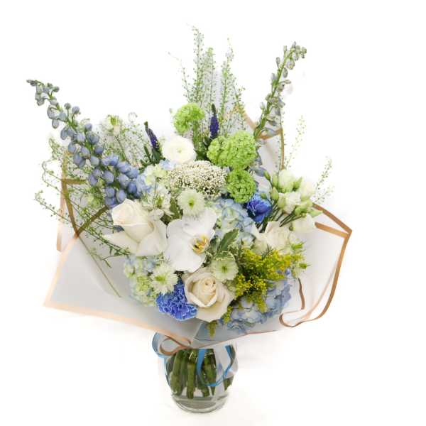 Bouquet of white, blue, and green flowers in a glass vase