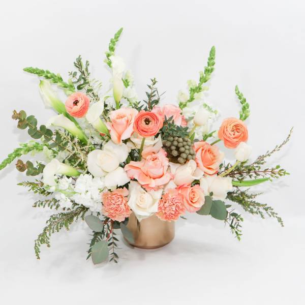 Peach and white bouquet in a gold vase