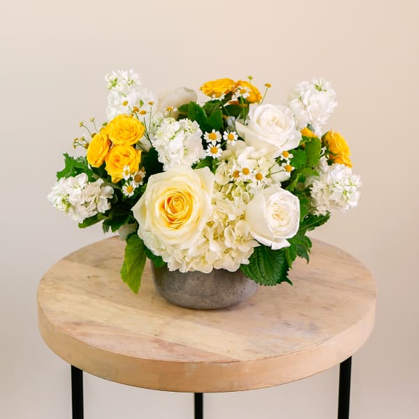 Yellow and white roses arranged in a gray bowl vase