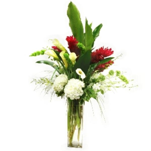 Tall floral arrangement with red, white, and green blooms in a clear glass vase