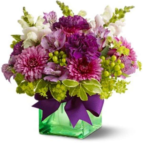 Purple and pink mixed bouquet in a green glass vase with a ribbon