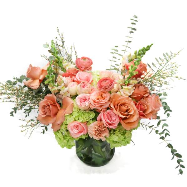 Peach and pink rose arrangement in a dark glass vase