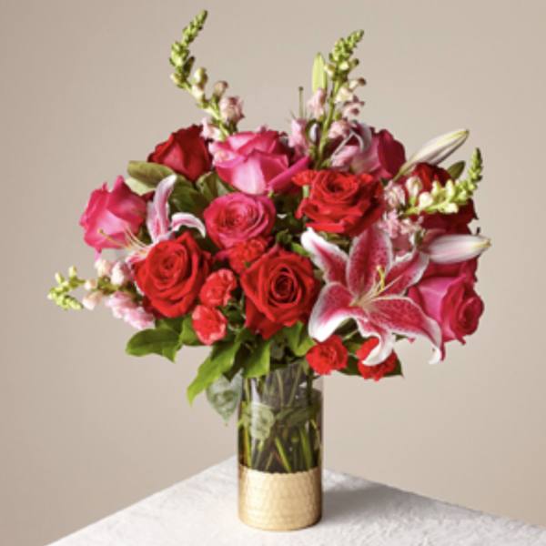 Bouquet of red and pink roses with lilies in a glass vase