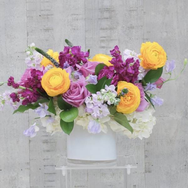 Bouquet of yellow, pink, and lavender flowers in a white vase