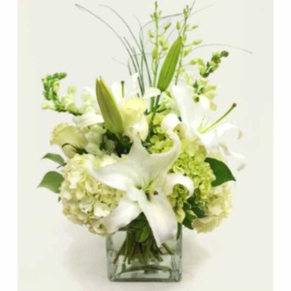 White lilies and pale green hydrangeas in a clear glass vase