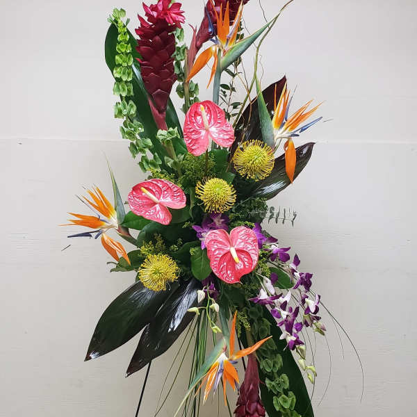 Tall tropical standing spray with red, orange, pink, and green flowers on a black metal easel