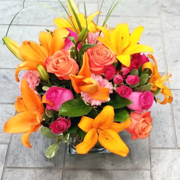 Bright bouquet of orange lilies and pink roses in a glass vase
