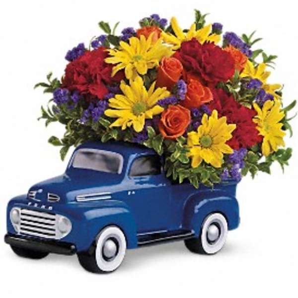 Colorful mixed flower arrangement in a blue ceramic toy truck container