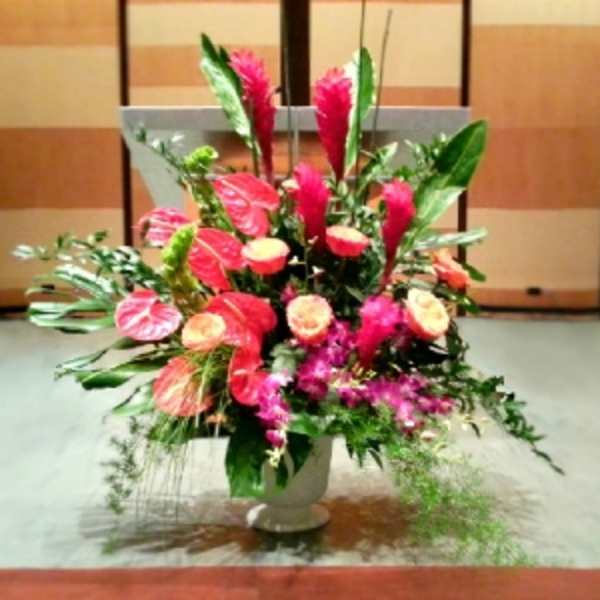 Large pink floral arrangement in a white pedestal vase
