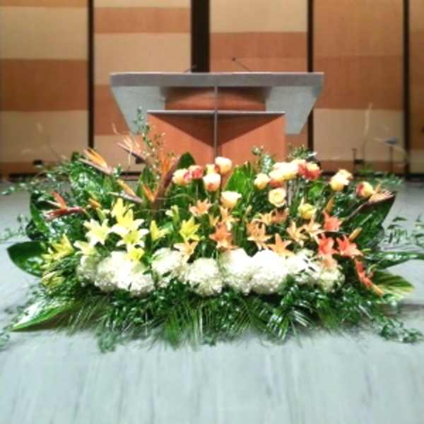 Large low altar arrangement with white hydrangeas, yellow lilies, peach roses and lush greenery