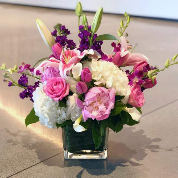 Pink and white floral arrangement in a square glass vase
