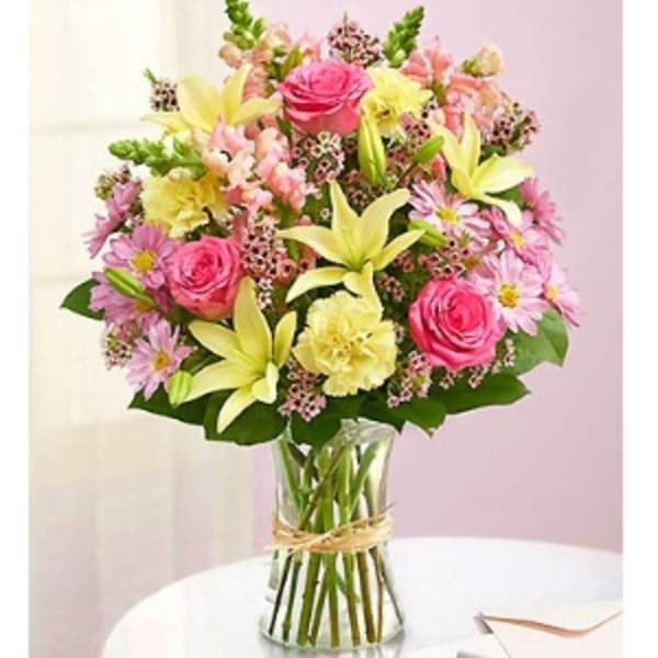 Mixed bouquet of pink roses, lilies, and daisies in a glass vase