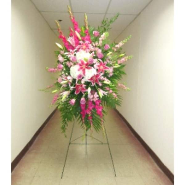 Tall pink and white standing spray with lilies and roses on a metal easel.