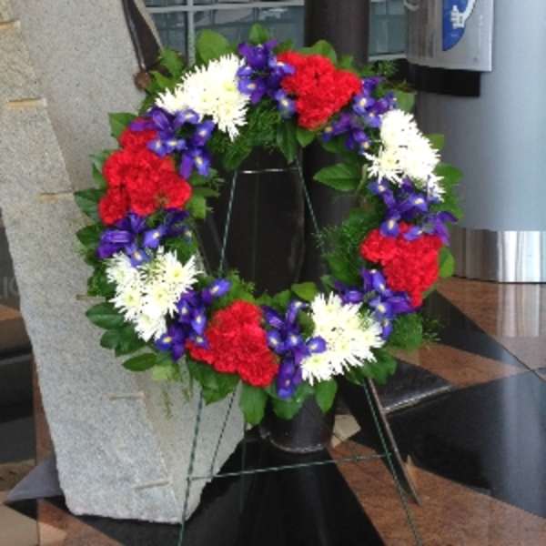Patriotic standing wreath with red, white, and purple flowers on a metal easel