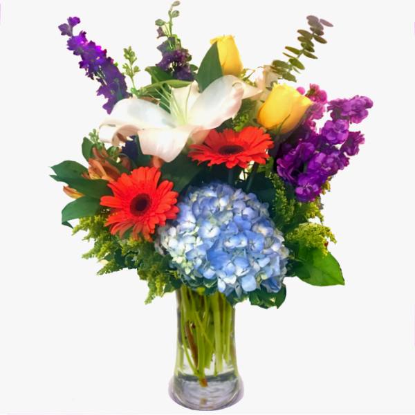 Mixed bouquet with lilies, gerbera daisies, hydrangea, and roses in a glass vase