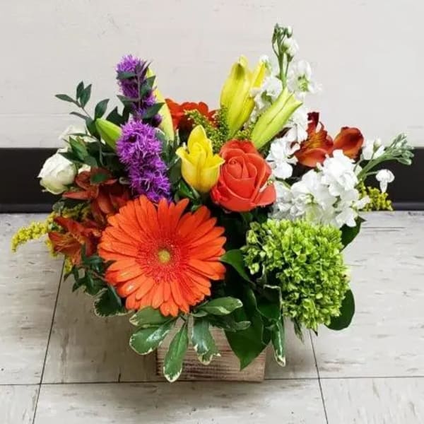 Mixed bouquet in a square box with orange, red, yellow, white, and purple flowers