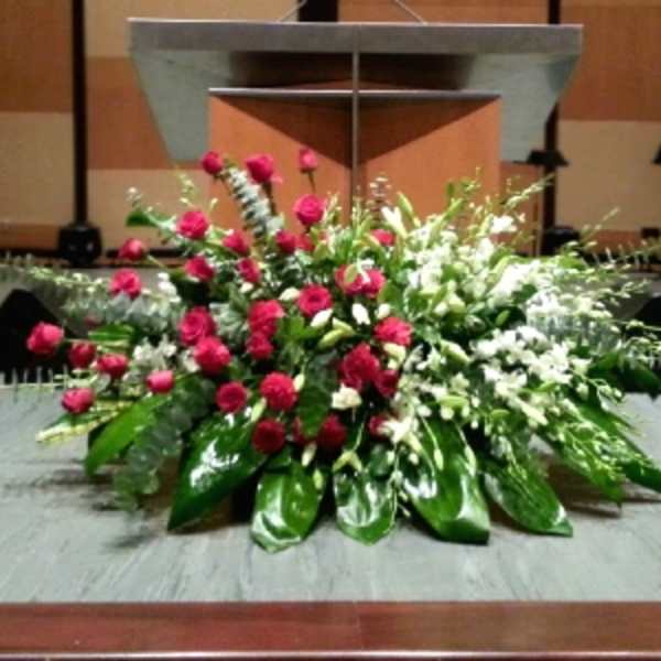 Large red and white floral spray with glossy green leaves arranged in front of a podium.