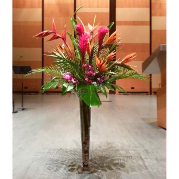 Tall tropical floral arrangement in a floor vase with pink and orange blooms