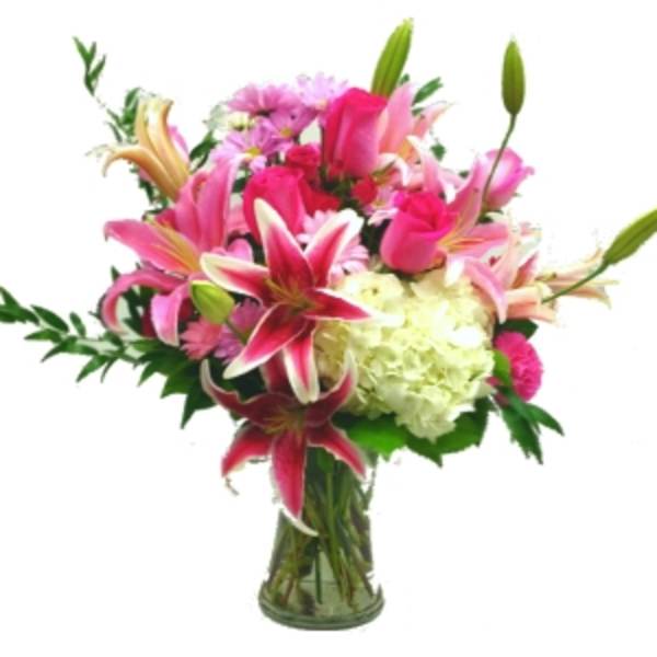 Pink lilies and roses in a glass vase with white hydrangea