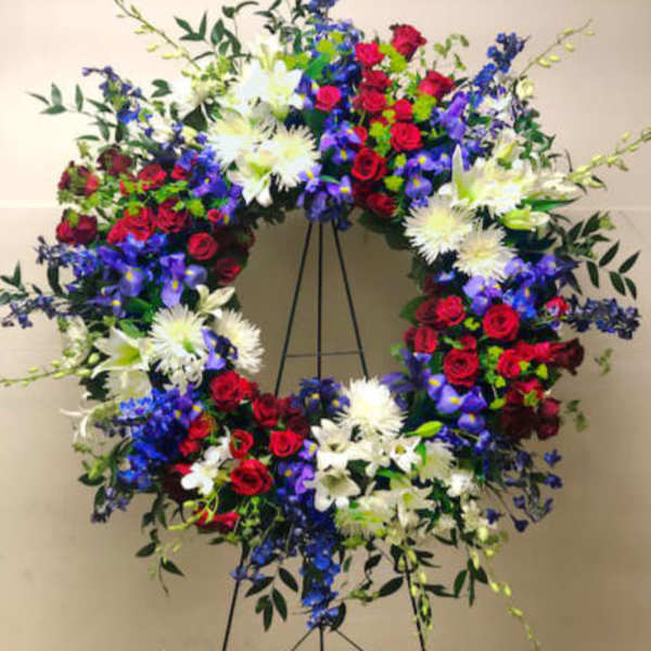Large circular floral wreath on a stand with red, white, and blue flowers