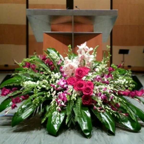 Large pink and white floral arrangement displayed in front of a podium on a stage