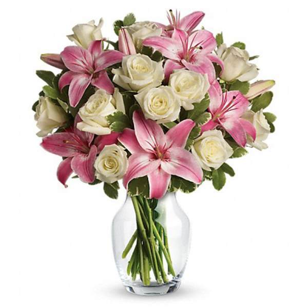 Pink lilies and white roses arranged in a clear glass vase