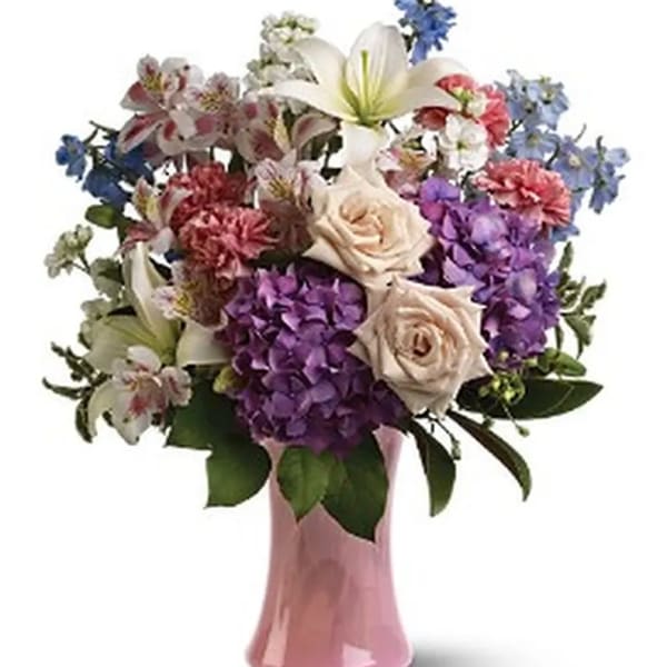 Mixed bouquet of roses, lilies, hydrangeas, and alstroemeria in a pink vase