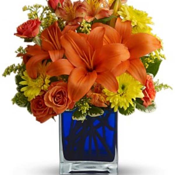 Orange lilies and yellow daisies in a blue glass vase