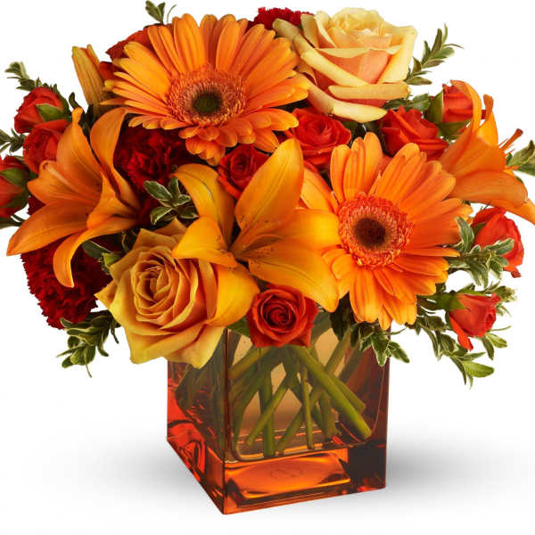 Orange and red mixed bouquet in a square glass vase