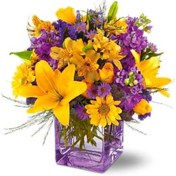 Purple and yellow mixed flower bouquet in a square glass vase